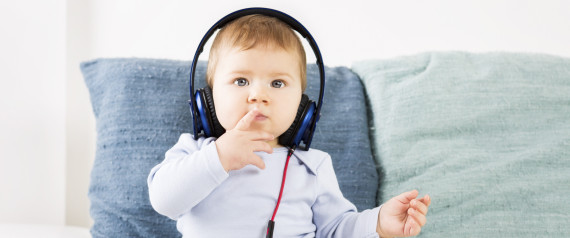 Adorable baby boy listening music at earphones.